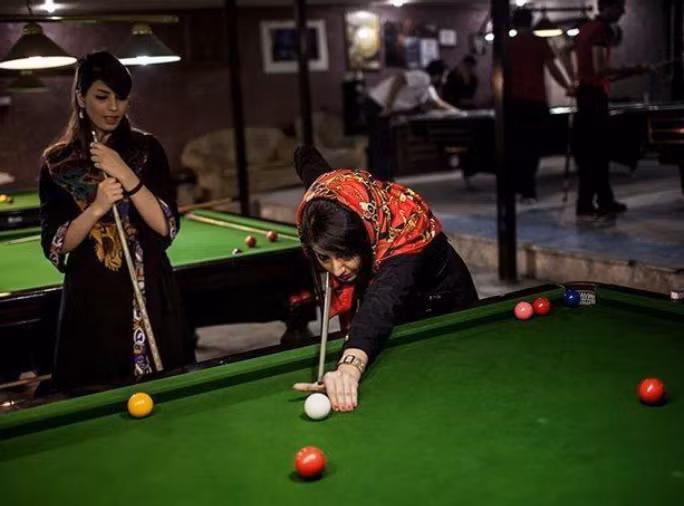 Hai người phụ nữ chơi bi-a tại một điểm giải trí.