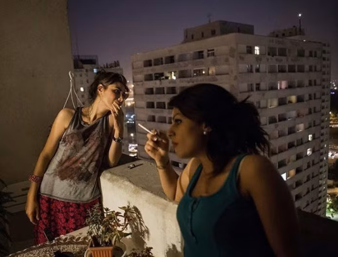 Hai người phụ nữ Iran đứng hút thuốc và trò chuyện ngoài ban công.
