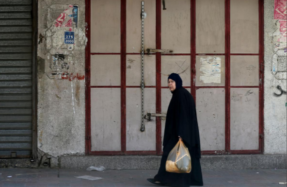 Một phụ nữ Palestine đi qua cửa hàng bị đóng cửa ở phía nam Dải Gaza ngày 15/5.