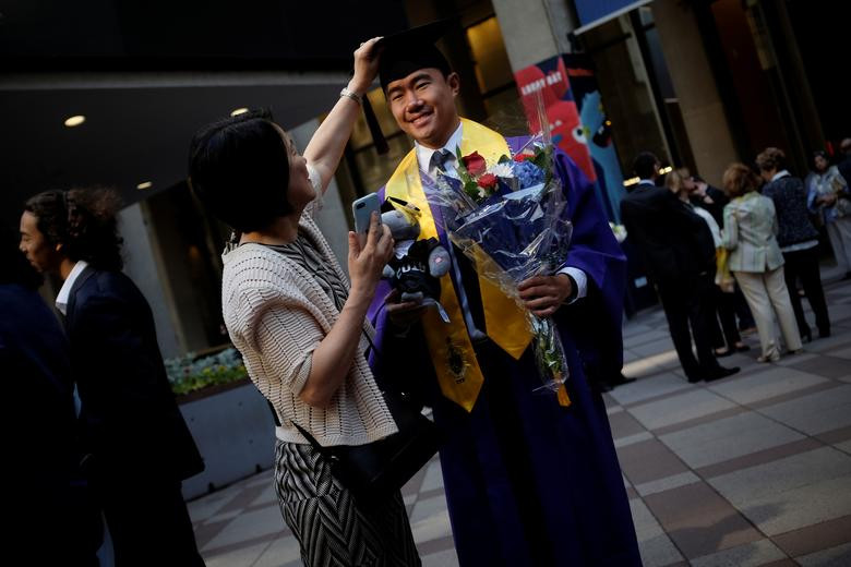 Một nam sinh Trường Kinh doanh thuộc Đại học New York cười tươi khi được mẹ chỉnh mũ để chụp ảnh lưu niệm trong ngày ra trường hôm 24/5.