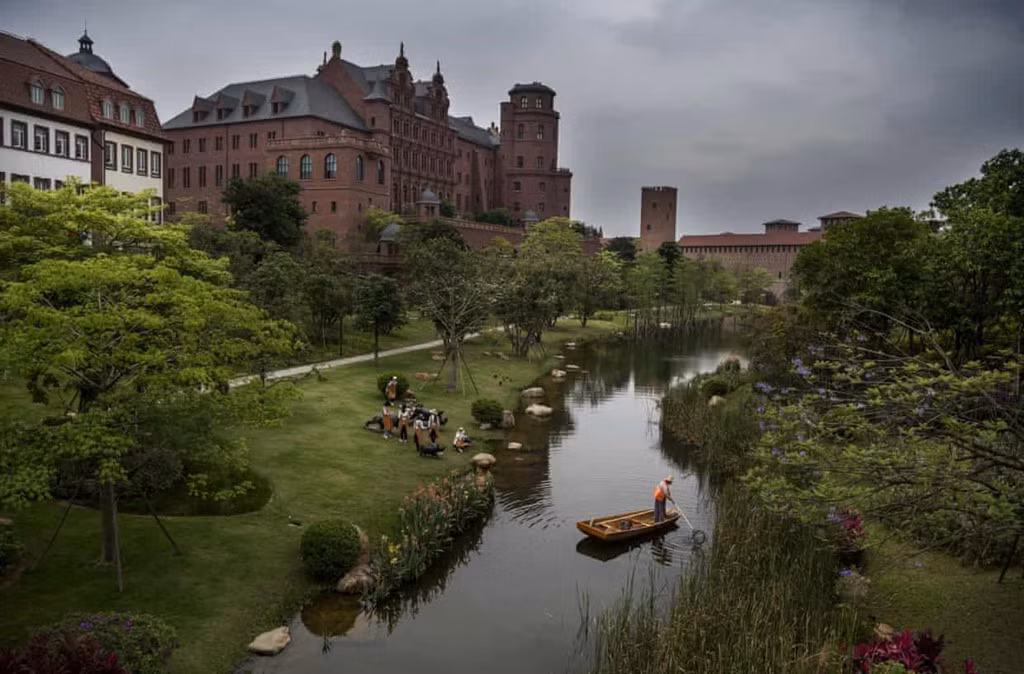 Một nhân viên đang dọn rác trên mặt hồ trong khuôn viên của Huawei. Ảnh: Getty Images.