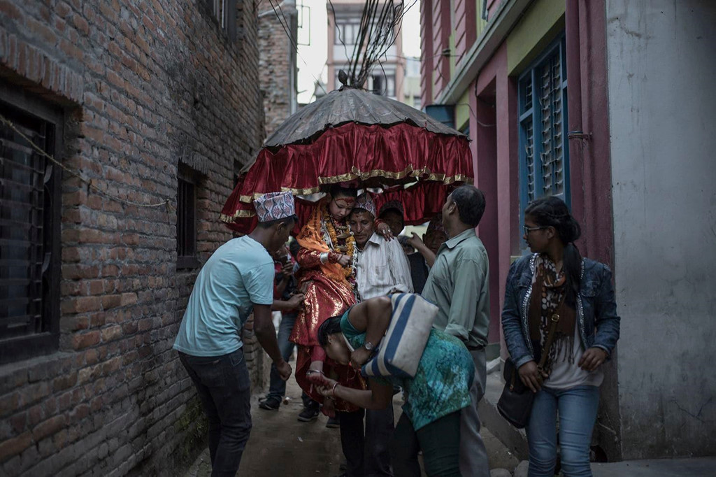 Những người họ hàng là nam giới đang rước Unika, người từng là nữ thần sống của Patan, đến ngôi đền nơi em ở. Unika, 11 tuổi, nói với nhiếp ảnh gia Contreras Coll rằng trong thời gian làm Kumari, “điều em thích nhất là làm người khác vui”. Ảnh: Maria Contreras Coll.