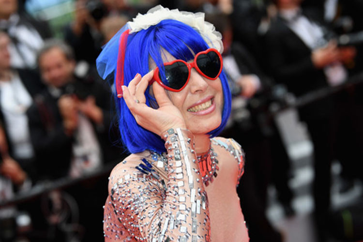 Cô nhuộm tóc xanh, diện váy ngắn kết hợp với tất dài màu đen, đi giày cao gót màu đỏ và đeo mắt kính hình trái tim. Ảnh: Zimbio