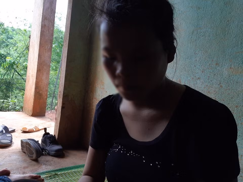 Bé M. lặng lẽ ngồi trong nhà.