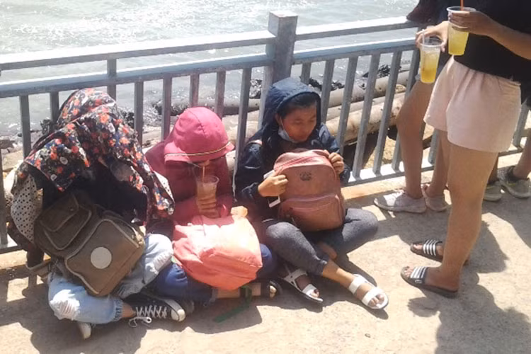 Một số khách du lịch mỏi mệt ngồi giữa nắng trưa gay gắt chờ tàu đò.