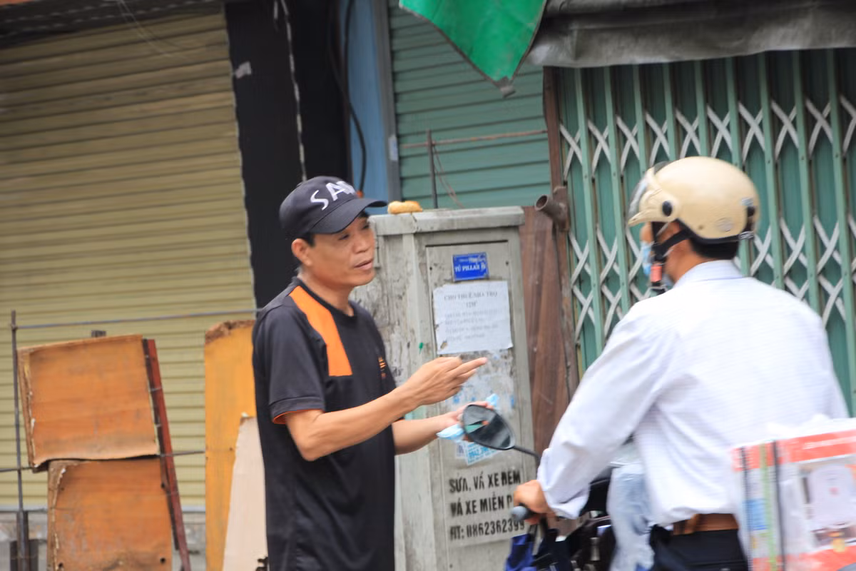 Người đàn ông không đeo khẩu trang vô tư đứng giữa đường nói chuyện.