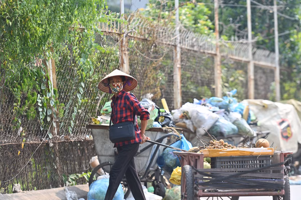 Người bán hàng rong chật vật kéo xe hàng của mình đi qua bãi rác.