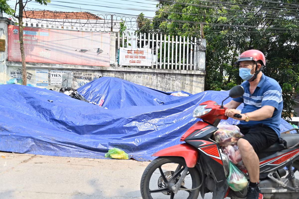 Để hạn chế mùi hôi thối bốc ra từ các đống rác này, công nhân vệ sinh môi trường phải phủ tạm một lớp bạt lên trên.