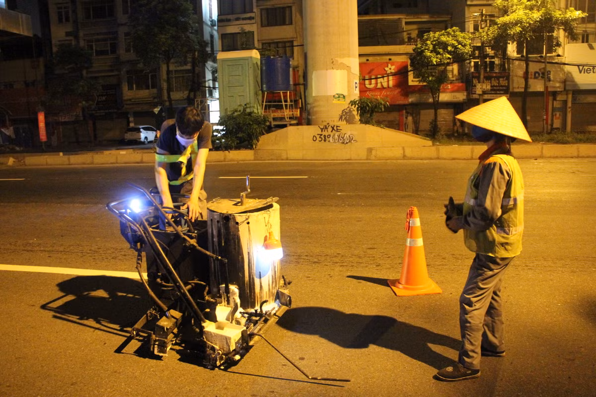 Thời điểm PV ghi nhận đã là 2h sáng 25/8, các công nhân vẫn miệt mài công việc của mình trên Quốc lộ 32 - tuyến đường huyết mạch phía Tây Hà Nội. Những vị trí vạch kẻ đường bị mờ, khuyết màu sẽ được công nhân "tô" lại đậm nét nhằm bảo đảm ATGT.