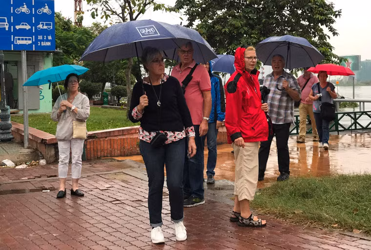 Du khách che du dạo chơi ven bến Bạch Đằng.