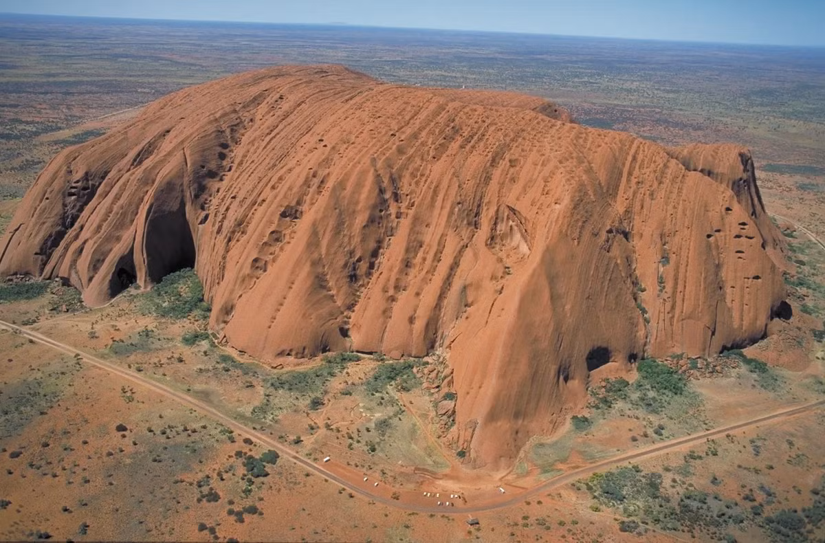 8. Tảng đá Uluru (Ayers Rock) - Úc: Uluru, còn được gọi là Ayers Rock, là một trong những tảng đá nguyên khối lớn nhất và nổi tiếng nhất thế giới. Nằm ở trung tâm nước Úc, Uluru cao 348 mét và có chu vi khoảng 9,4 km. Tảng đá này được biết đến với khả năng thay đổi màu sắc theo thời gian trong ngày, từ màu đỏ rực rỡ vào buổi sáng sớm đến màu cam và tím vào lúc hoàng hôn. Uluru cũng là một địa điểm linh thiêng của người thổ dân Anangu, với nhiều truyền thuyết và câu chuyện văn hóa gắn liền với nó.(Ảnh: Britannica)