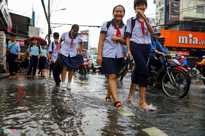 Học sinh trường THCS Trương Văn Ngư (đoạn gần chợ Thủ Đức) tháo giày để di chuyển qua vùng nước ngập.