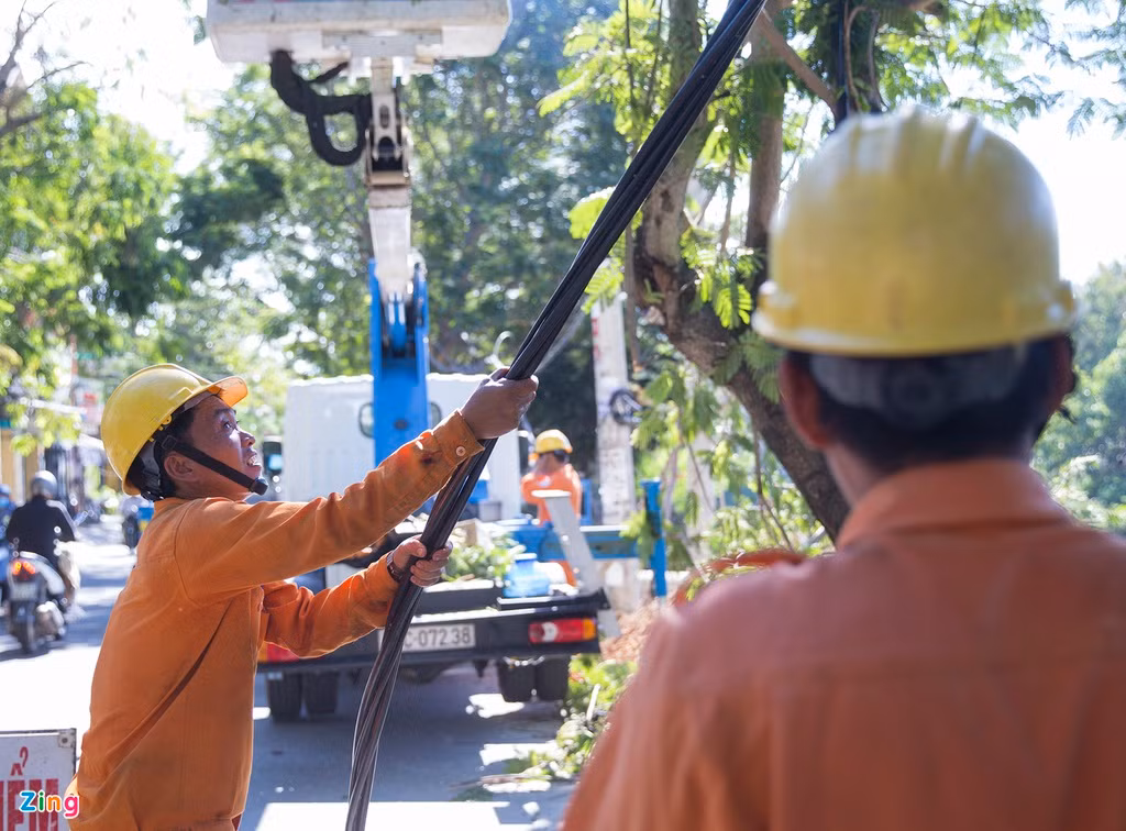 Ngày 23/9, nhiều công nhân đang đấu nối dây điện bị đứt. Những nơi chưa có cột điện mới thay thế, họ phải gác tạm dây lên cây xanh ven đường.