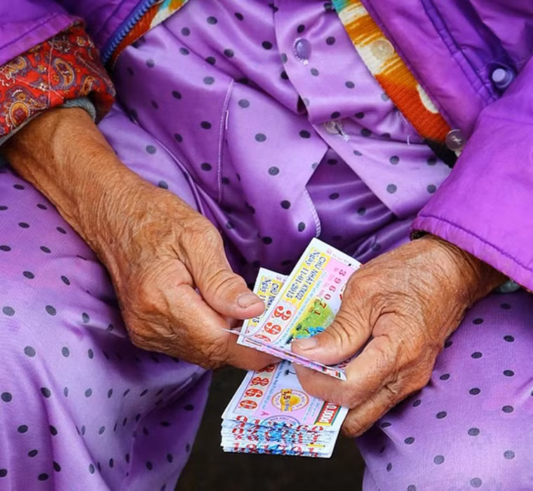 Một người phụ nữ lớn tuổi cầm vé số đi bán ở Huế.