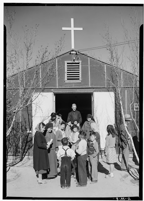 Một nhóm người tụ tập bên ngoài một tòa nhà với cây thánh giá ở trên mái nhà.