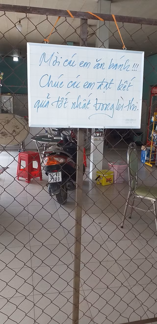 Bên cạnh giá hàng, thầy giáo đặt 1 tấm bảng nhỏ có ghi lời chúc của thầy gửi đến các trò của mình: "Mời các em ăn bánh. Chúc các em đạt kết quả tốt nhất trong kỳ thi". Ảnh: Facebook