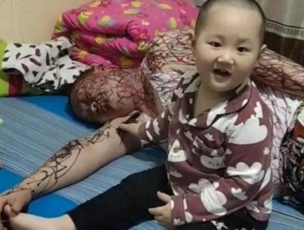 Trong hình, bé gái này đang dùng bút vẽ kín người của một người đàn ông. Người này đang ngủ nên nằm im mặc cho cháu vẽ thoải mái.