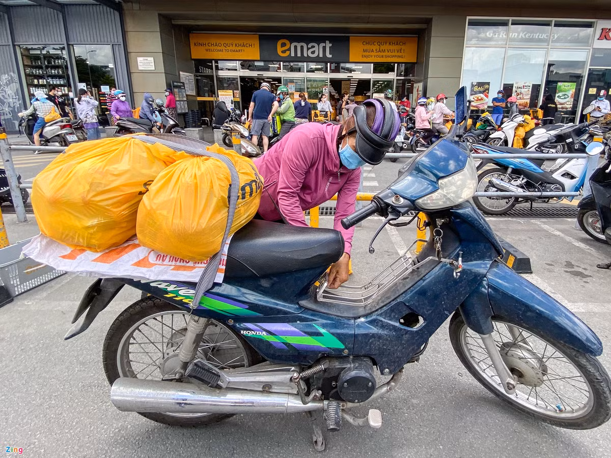 Chị Nguyễn Thị Kim Nhung (ngụ Gò Vấp) đang chở những túi hàng vừa mua được từ siêu thị. Chị đến từ 9h, mua hàng hết 30 phút và phải chờ gần 3 giờ mới có thể thanh toán được. "Thấy đông đúc cũng lo lắng nhưng hiện tại không nhiều siêu thị còn mở cửa, đành phải chịu đến đây mua thôi", chị Nhung chia sẻ.