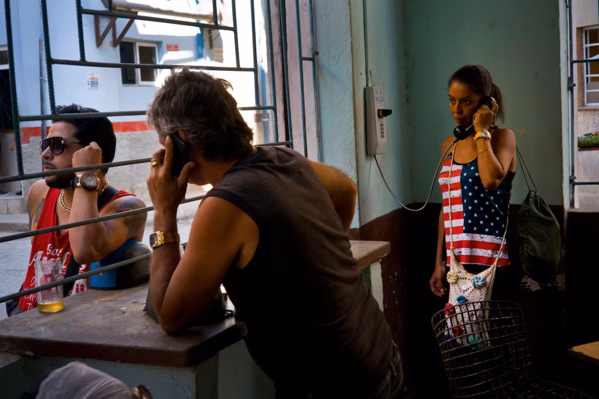 Những người dân địa phương tới cửa hàng cà phê. Trong đó, một người phụ nữ mặc áo in hình cờ nước Mỹ đang nói chuyện điện thoại. Ảnh USN