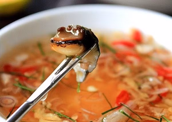 Cuối cùng cho gừng, lá chanh, rau mùi, sả bào vào nước mắm đường, khuấy đều, nếm lại lần nữa cho thật vừa ăn rồi cho vỏ quất băm vào bát nước chấm.