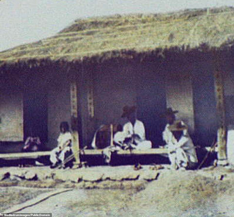 Gia đình một người dân địa phương đang ngồi trò chuyện trước hiên ngôi nhà lá đơn sơ.