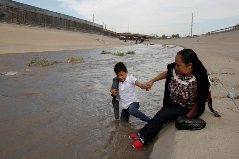 Hai người nhập cư đến từ Trung Mỹ đang chuẩn bị lội qua sông Ri Grande ngày 11/6.