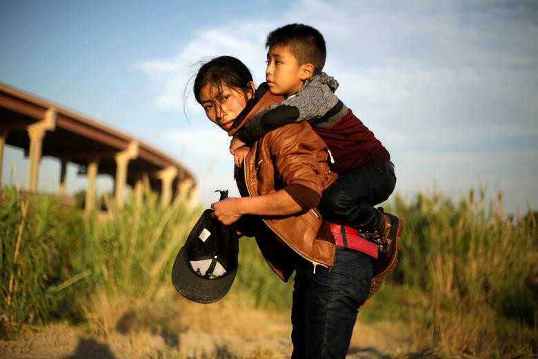 Người phụ nữ Guatemala cõng con nhỏ trên lưng trước khi vượt sông Rio Grande tuần trước.