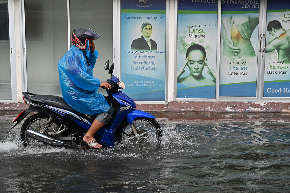 Người đàn ông đi xe máy qua con phố ngập lụt ở thủ đô Bangkok, Thái Lan. Ảnh: AJ. Mời độc giả xem thêm video về một trận lũ lụt tại Ấn Độ (Nguồn: VTC14)