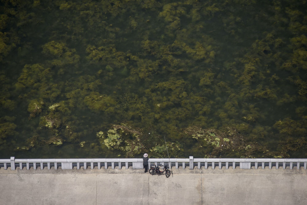 Người đàn ông câu cá đứng trên bờ sông Taedong.