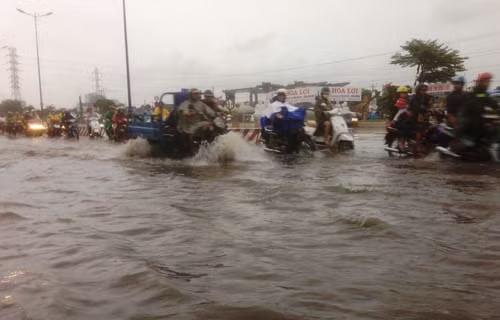 Người và xe bì bõm vượt qua nước ngập để trở về nhà.