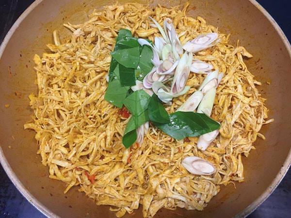 Đun nóng 3 thìa dầu ăn, cho hạt điều vào chưng cho có màu đỏ đẹp, vứt bỏ xác. Cho tỏi và ớt sừng vào phi thơm, sau đó cho tiếp phần còn lại của bột ngũ vị hương, bột ớt Hàn Quốc vào xào trong vài phút. Khi hỗn hợp có màu đẹp cho thịt gà đã xé cùng với sả và lá chanh cắt xéo vào. Hạ lửa nhỏ, đảo đều cho gà thấm gia vị khoảng 5-7 phút.