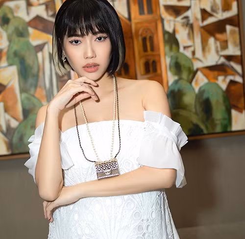 Chiếc túi siêu nhỏ màu ánh kim, trang trí đây đôi với hạt ngọc trai được Diệu Nhi chọn để tạo điểm nhấn cho váy khoe vai trần ton-sur-ton bốt cao cổ.