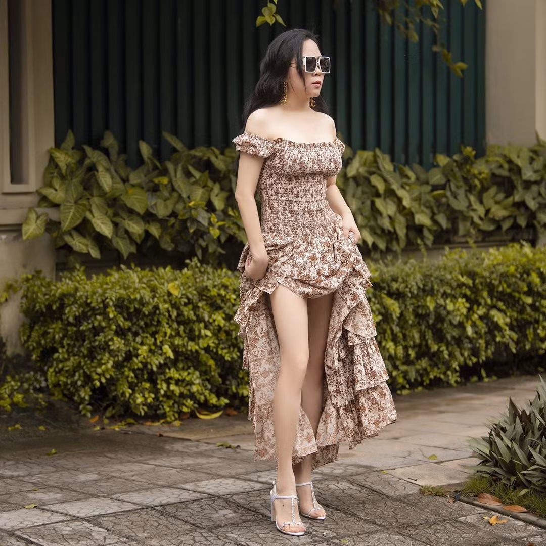 Phượng Chanel cực trẻ trung khi diện váy hoa maxi trễ vai, bèo nhún mix cùng phụ kiện trang sức, mắt kiếng bản to và giày cao gót dây xỏ ngón.