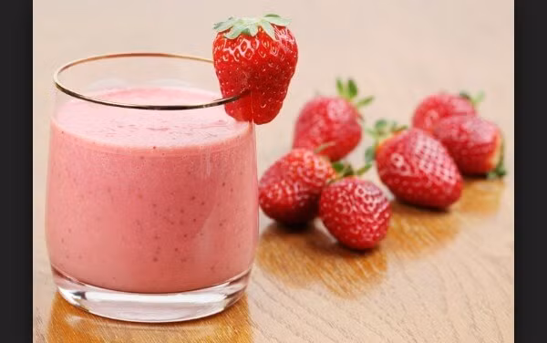 Xay chừng 1 phút, quan sát thấy sinh tố đã nhuyễn và mịn thì mình có thể cho ra cốc. Bổ đôi một quả dâu tây và cho vào để trang trí cho cốc sinh tố thêm phần hấp dẫn.