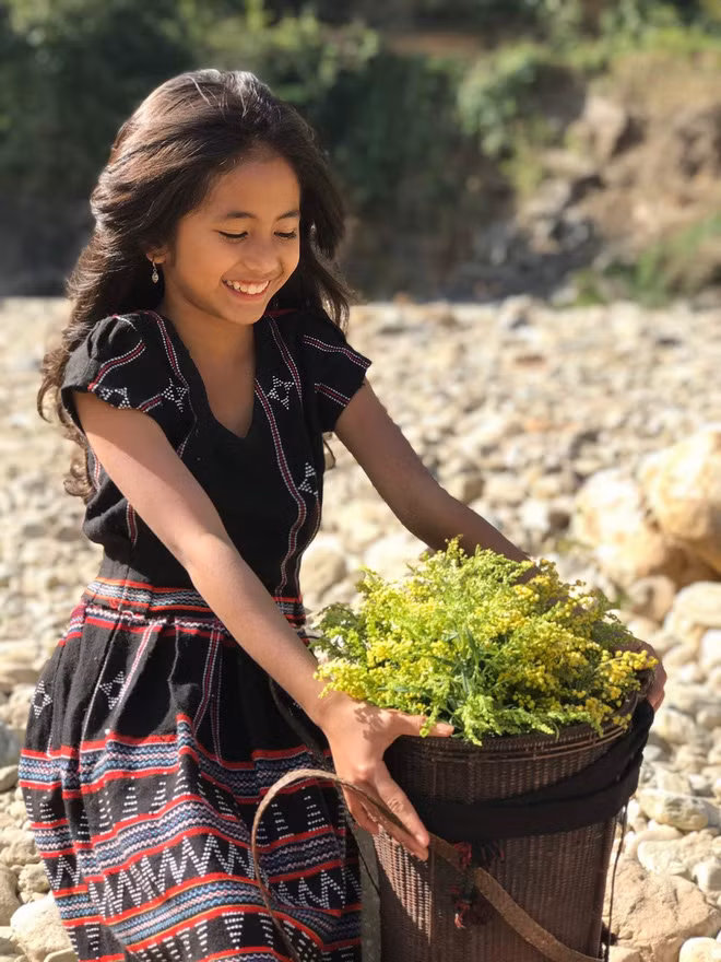 Dù chỉ mới 10 tuổi, nhưng cô bé đã sở hữu nét đẹp nổi bật, rạng ngời khiến nhiều người trầm trồ. Dẫu cuộc sống còn nhiều vất vả, nhưng trên môi của cô bé vẫn giữ được nụ cười tươi tắn, ánh mắt rạng rỡ ngây thơ như làm sáng rực cả một vùng núi rừng đại ngàn xanh tươi.