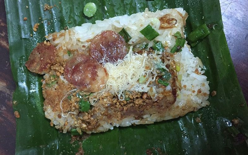 Một gói xôi nhà xác gồm một miếng xôi trắng bằng lòng bàn tay, phủ lên trên có pate mỏng, lạp xưởng, chà bông, đậu phộng và rưới chút mỡ hành phi… cắn tới đâu xé lá chuối tới đó, vị xôi hòa quyện vô cùng hấp dẫn.