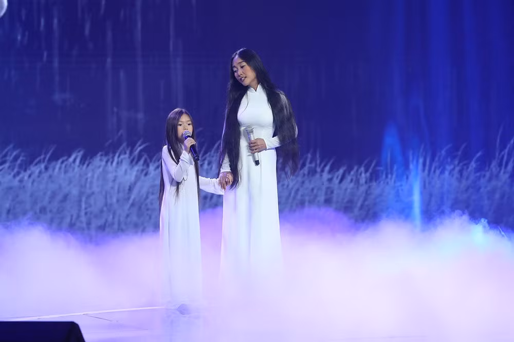 Hai mẹ con ca sĩ Đoan Trang nền nã trong tà áo dài trắng cùng biểu diễn trên sân khấu.