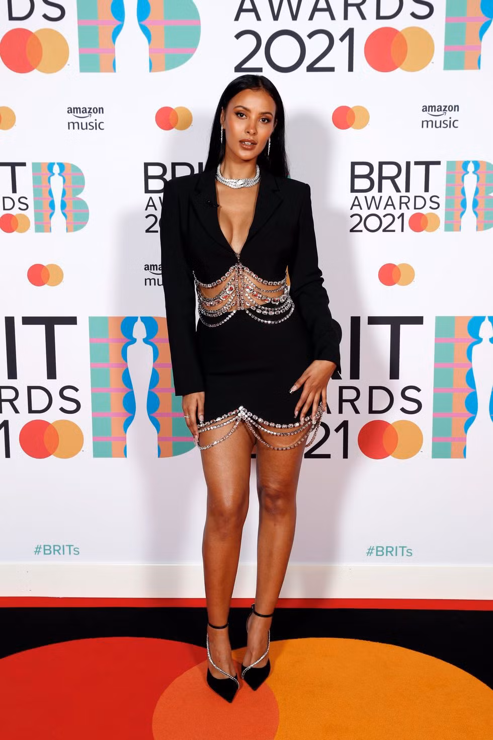 Maya Jama mặc váy đen có phần cổ khoét sâu với chi tiết đính cườm.