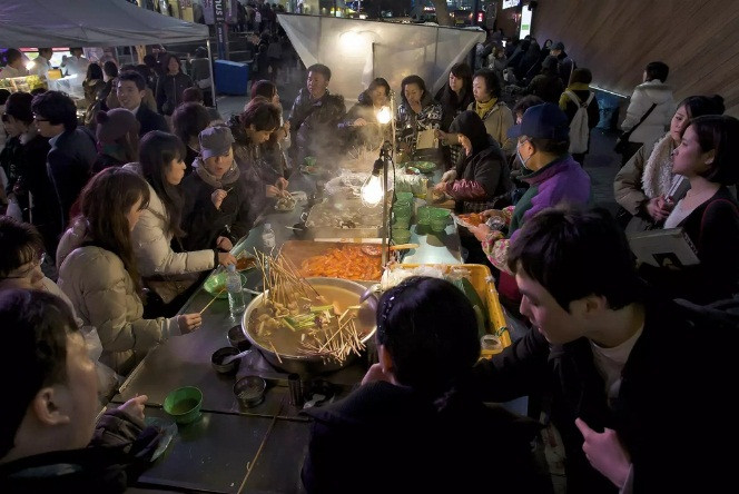 Tteokbokki có mặt khắp nơi ở Hàn Quốc. Món ăn đường phố phổ biến và rẻ tiền này có quanh năm nhưng trở nên phổ biến hơn vào mùa đông. Tteokbokki có nước sốt đặc làm từ cà chua, ớt cay... Người bán sẽ giữ món ăn nóng hổi trên khay hơi nước và bếp than. Mọi người có thể làm ấm cơ thể bằng cách đứng, ngồi gần xe đẩy hoặc quầy hàng khi ăn.