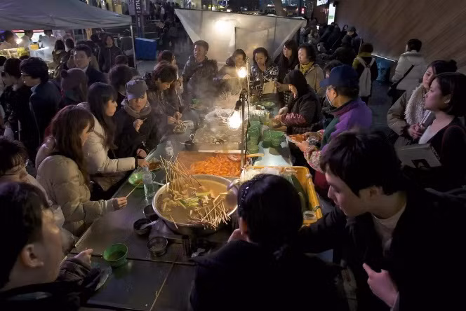 Tteokbokki có mặt khắp nơi ở Hàn Quốc. Món ăn đường phố phổ biến và rẻ tiền này có quanh năm nhưng trở nên phổ biến hơn vào mùa đông. Tteokbokki có nước sốt đặc làm từ cà chua, ớt cay... Người bán sẽ giữ món ăn nóng hổi trên khay hơi nước và bếp than. Mọi người có thể làm ấm cơ thể bằng cách đứng, ngồi gần xe đẩy hoặc quầy hàng khi ăn.