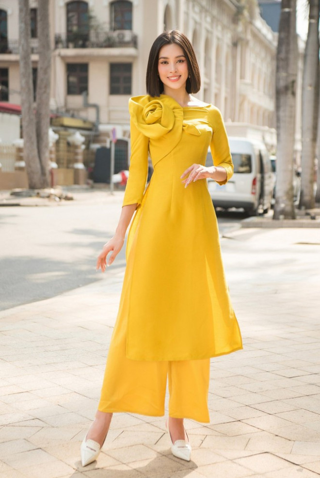 Còn hoa Hậu Tiểu Vy cũng diện áo dài cách tân màu vàng, điểm nhấn là phần xếp li hoa hồng trên cổ áo, duyên dáng đón Tết.