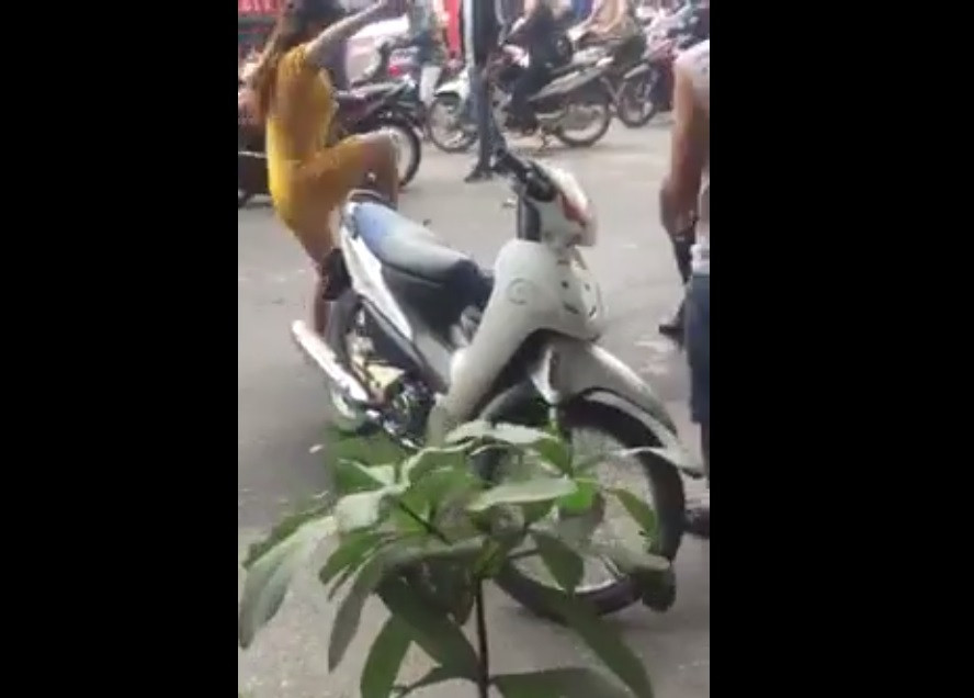 Cô gái mặc váy vàng bị chém hụt lao vào dùng chân đạp tới tấp kẻ chém mình.