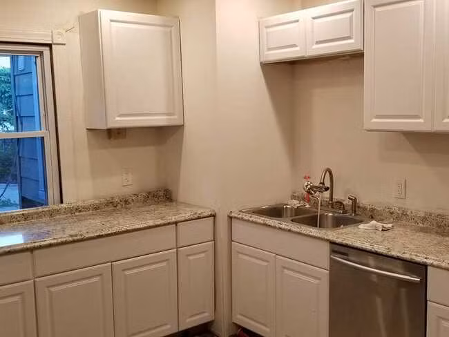 Hình ảnh căn bếp do chính Orr thiết kế và tự lắp đặt. Không gian cải tạo với tủ bếp màu trắng, mặt bàn bằng đá cẩm thạch, và các thiết bị mới.