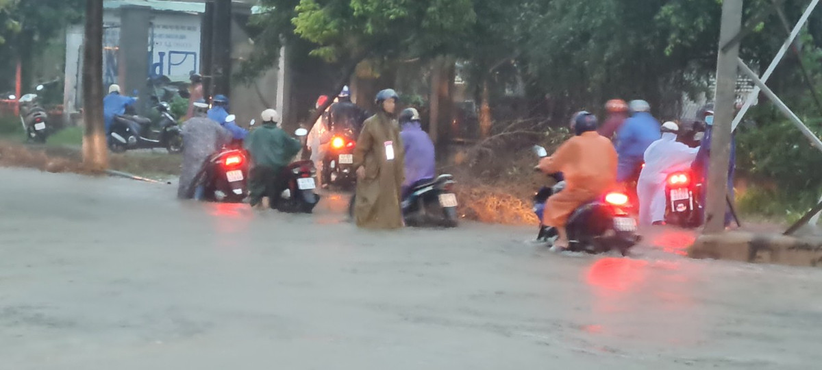 Xe máy dắt bộ leo vỉa hè để thoát đoạn đường ngập.