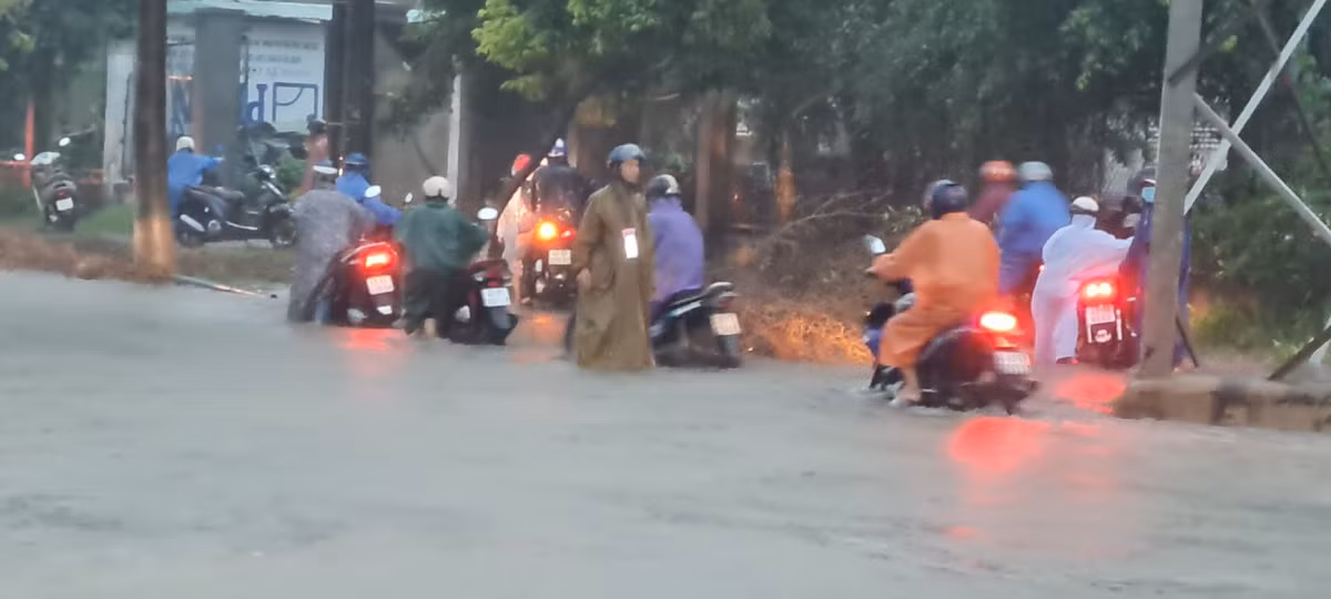 Xe máy dắt bộ leo vỉa hè để thoát đoạn đường ngập.