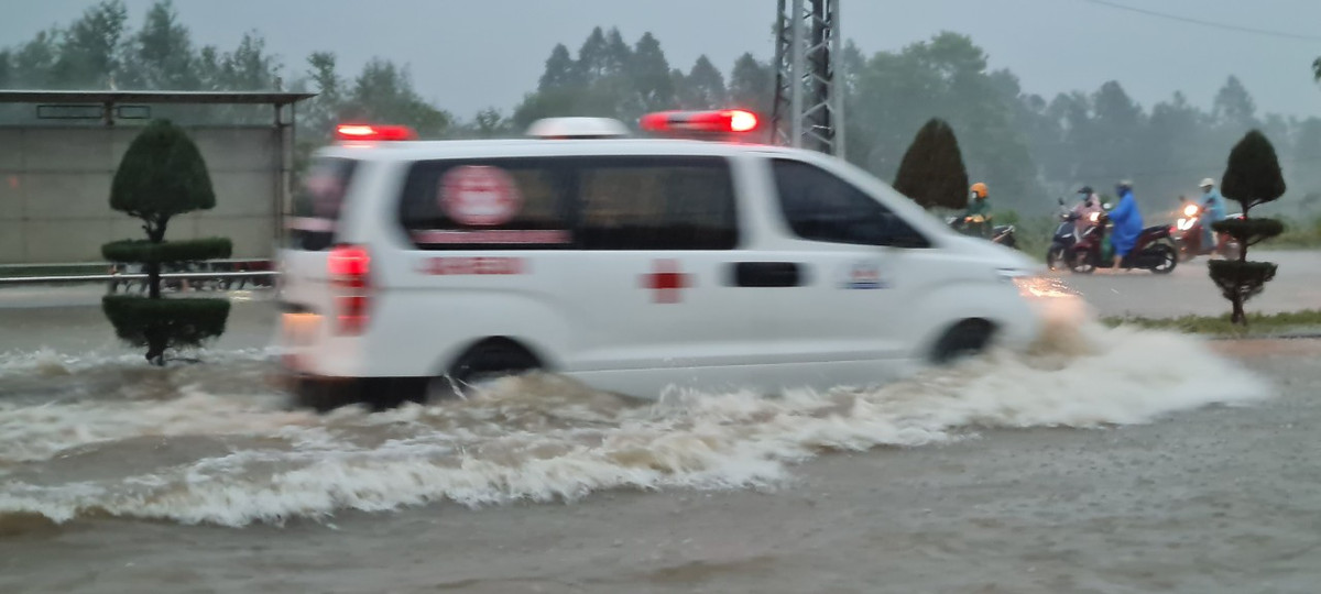 Một chiếc xe cấp cứu chạy băng băng giữa cơn mưa trắng trời.