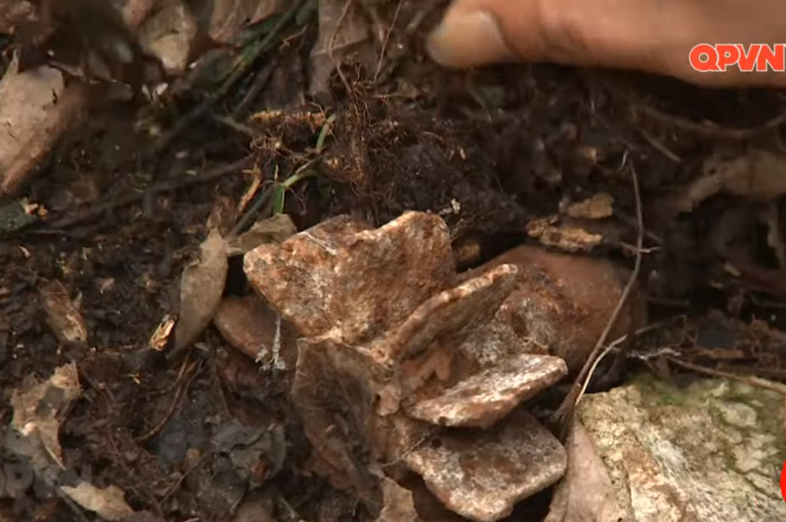 Một quả đạn cối còn sót lại bên cạnh những vật dụng của một chiến sĩ tham gia chiến đấu ở biên giới phía Bắc được tìm thấy trong một khe núi đá. Nguồn ảnh: QPVN.