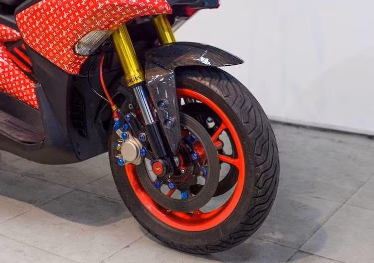 Ở phía trước, "dàn chân" của NVX 155 đã được độ lại khá "khủng" với cặp phuộc USD TXF thay cho phuộc nguyên bản cùng hệ thống phanh được nâng cấp lên đĩa kép, sử dụng đĩa phanh bằng sợi carbon như xe đua và heo từ hãng ISR.