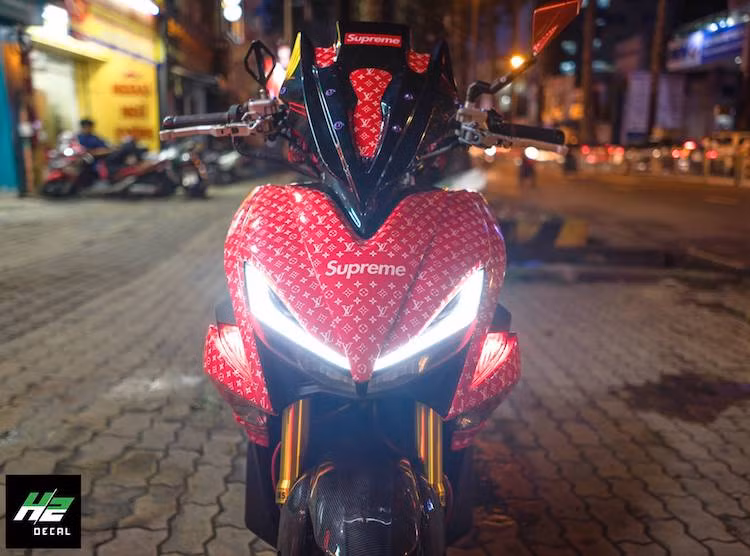 Sử dụng NVX làm nền tảng, một biker trẻ tại Sài Gòn đã độ lại chiếc xe tay ga thể thao này với kiểu dáng cực "độc" với dàn áo mang thương hiệu Louis Vuitton "đỏ choé", hoàn toàn không "đụng hàng". Chưa dừng lại ở đó, bản độ còn sở hữu một loạt các món phụ tùng nâng cấp độc đáo.