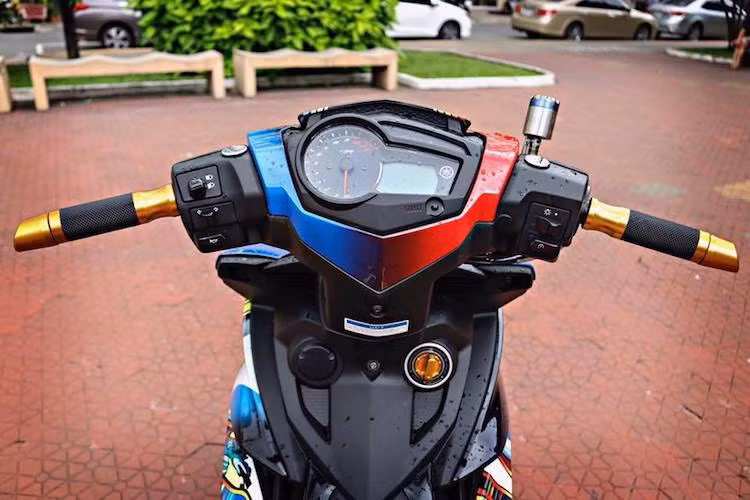 Ở phía trên khu vực tay lái của bản độ vẫn giữ lại thiết kế và cùm công tắc nguyên bản từ Yamaha Exciter 150. Tuy nhiên, 2 bên tay lái có sự xuất hiện của cặp bao tay Rizoma Lux, gù xéo Rizoma, bình dầu Bonamici cùng cùm phanh/côn đồng bộ từ Accossato.